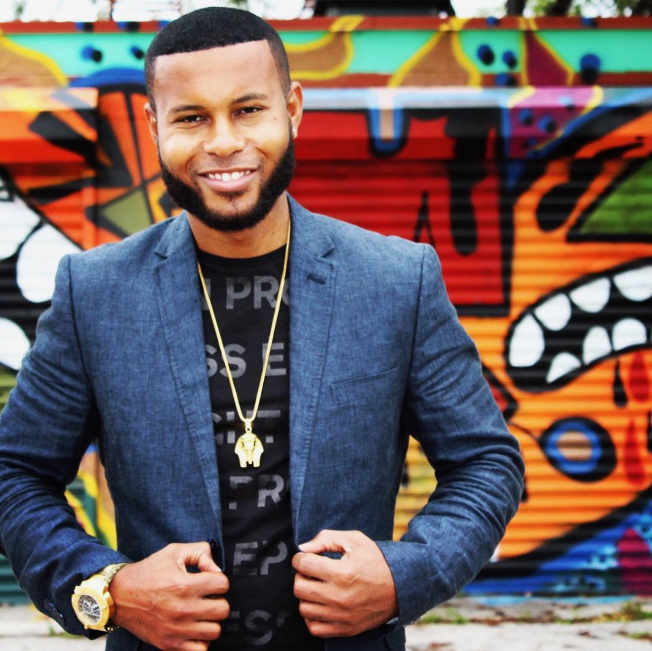 Anthony Alexander smiling in a blue blazer before a colorful mural