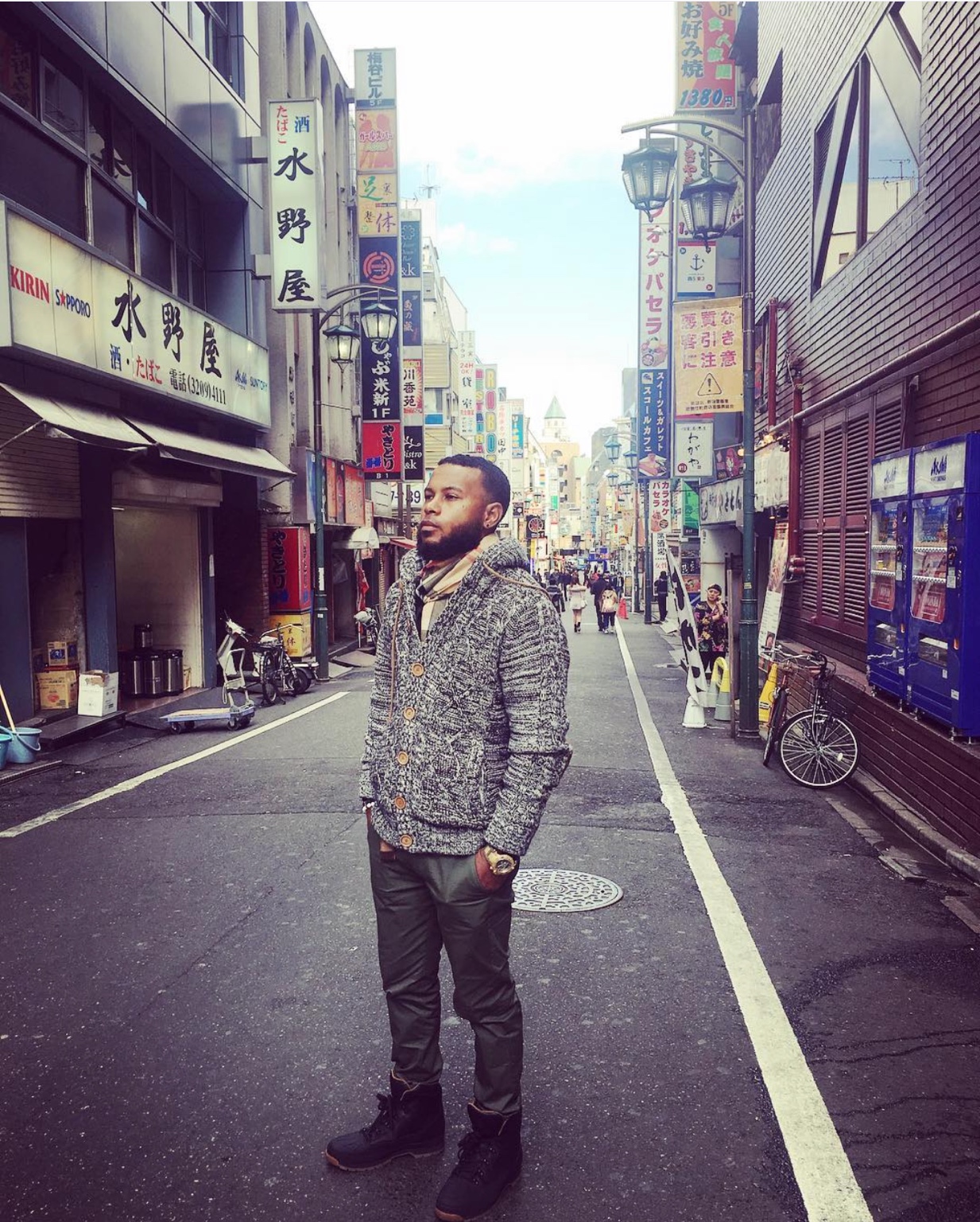 Anthony Alexander wearing a textured cardigan and scarf on a city street