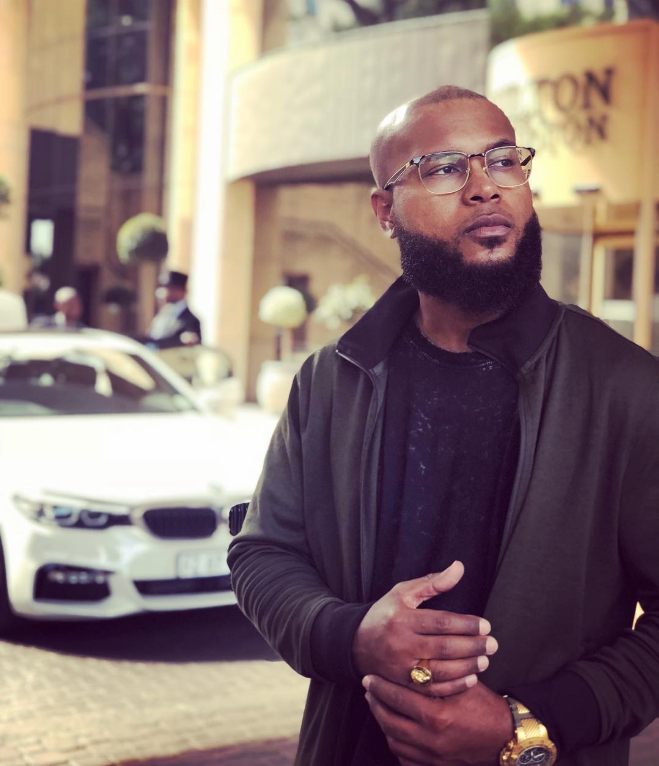 Anthony Alexander wearing glasses and a black outfit outdoors