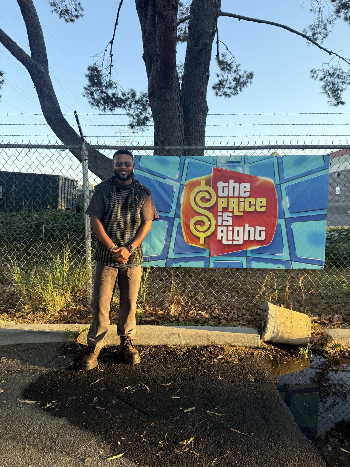 Anthony Alexander standing beside a colorful The Price Is Right banner outdoors
