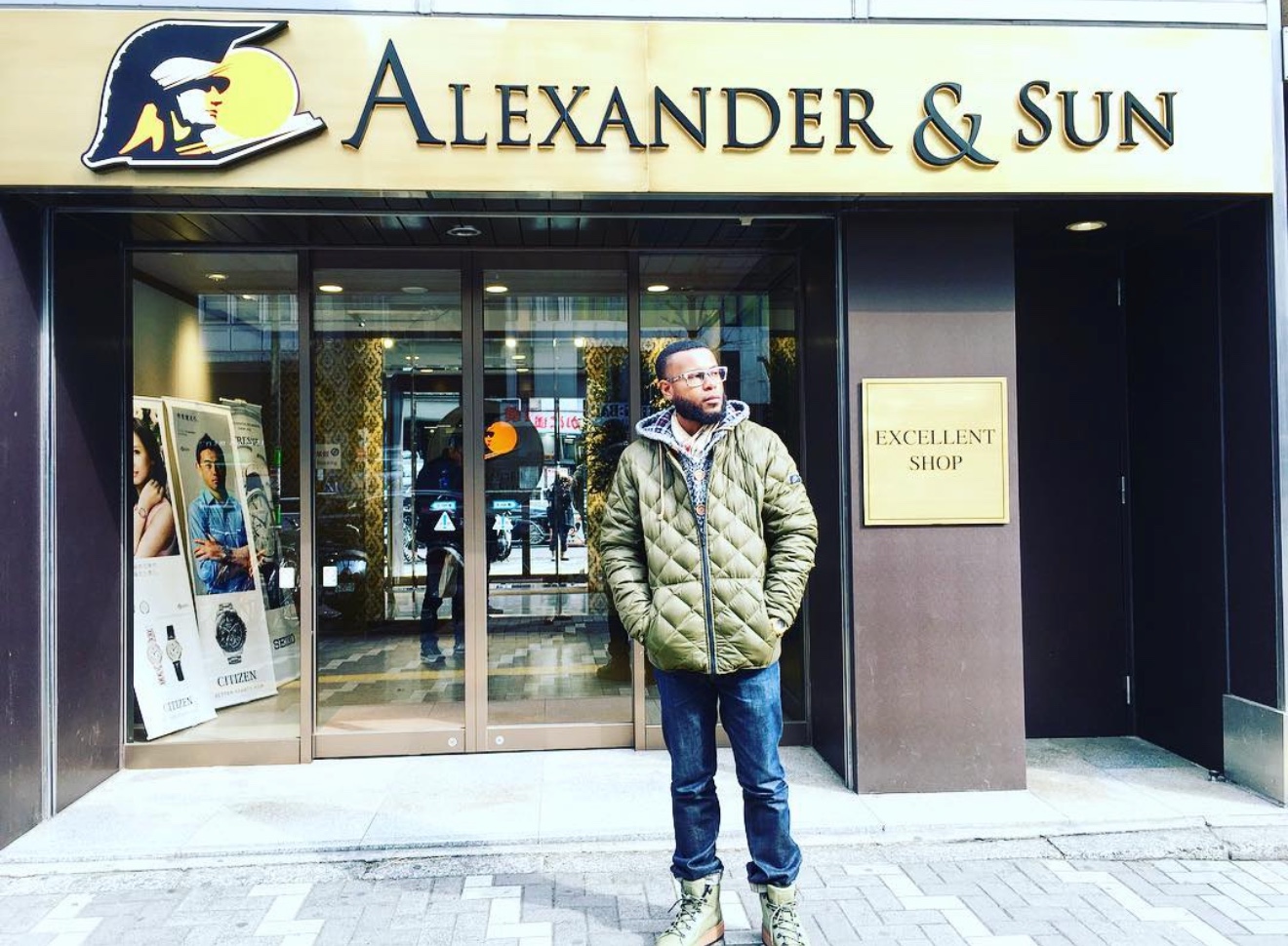 Anthony Alexander in a green quilted jacket outside the Alexander and Sun storefront